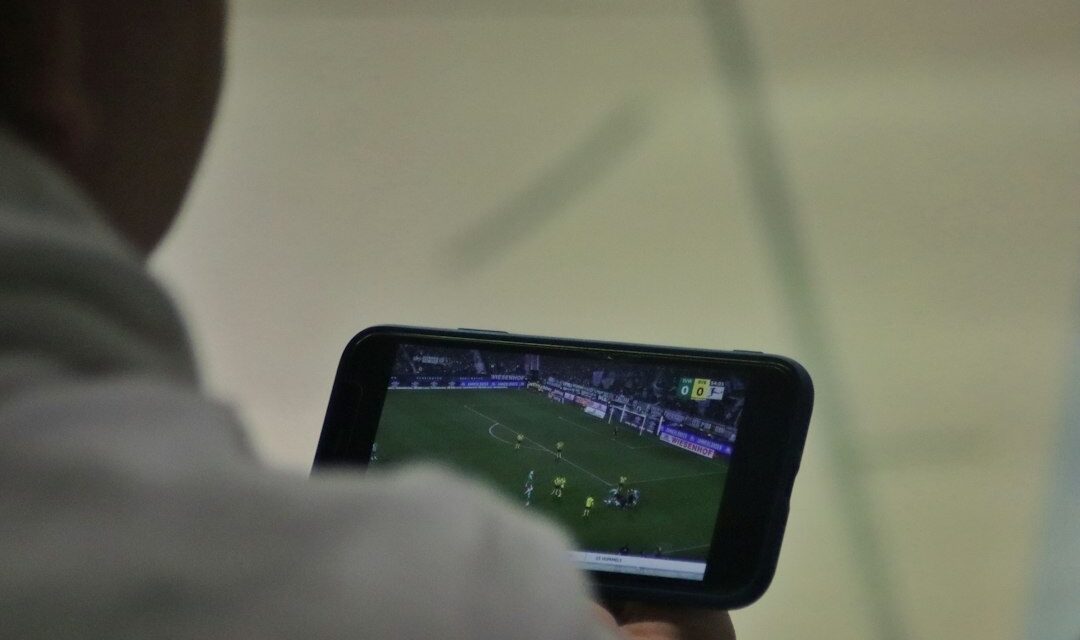 Man following a football match on his phone – best betting sites Nigeria